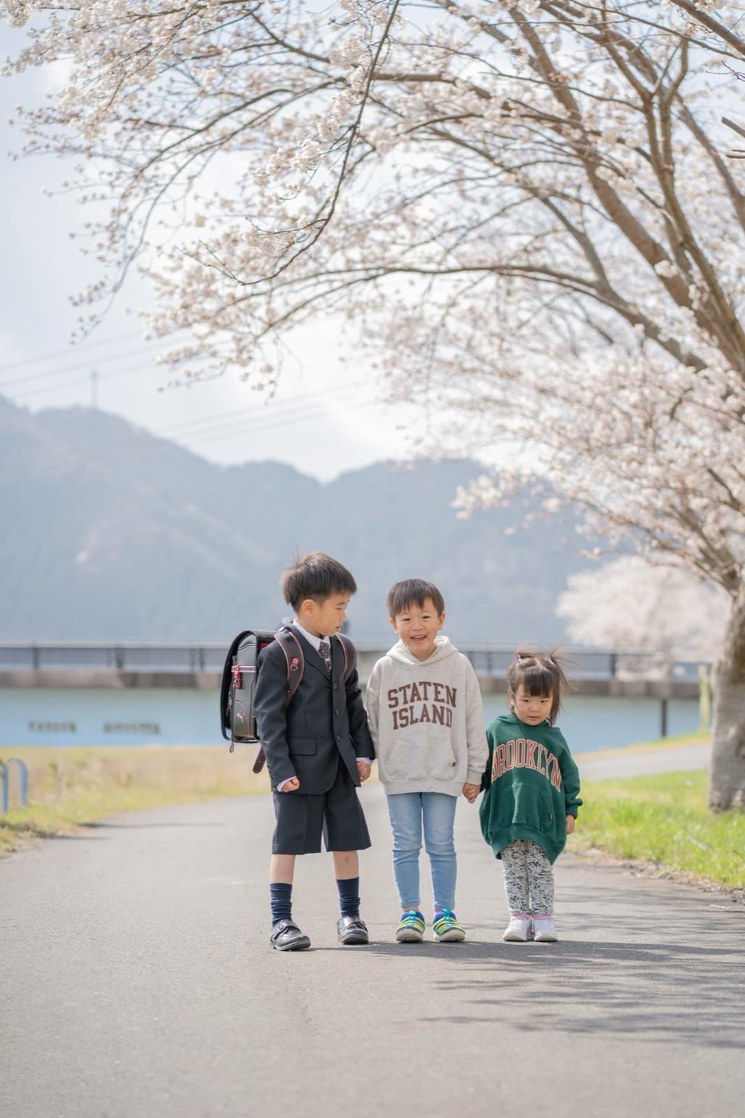 桜並木の下のきょうだい 3 人