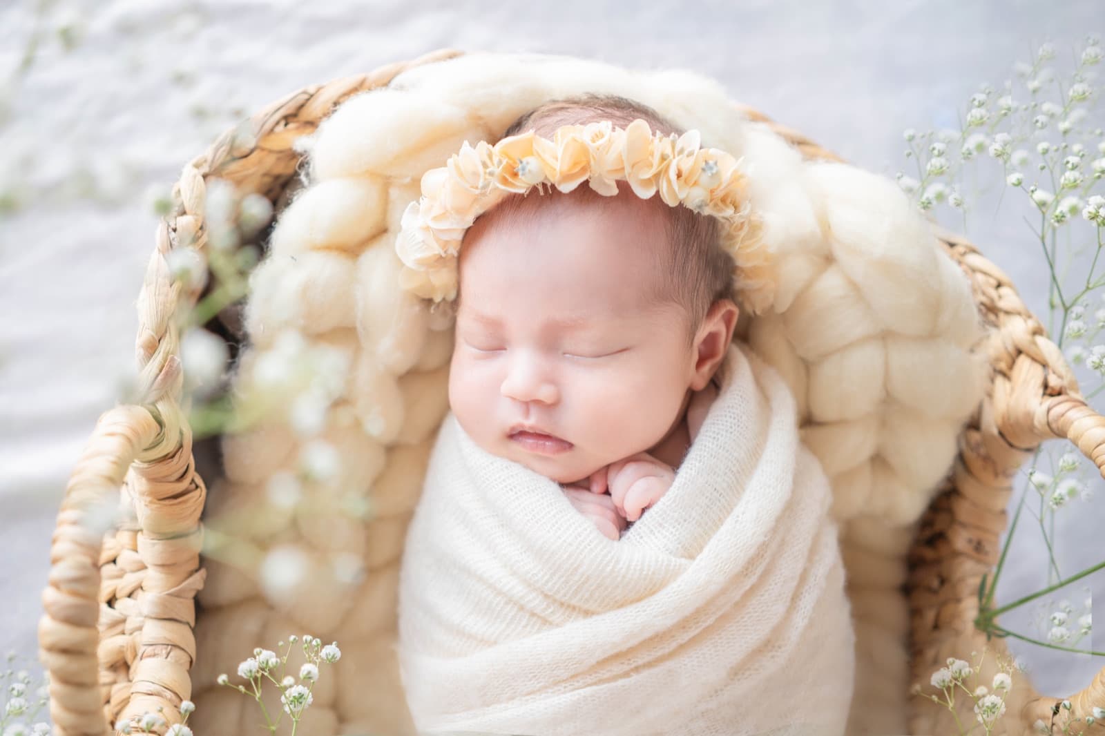 花冠をつけてかごの中で眠る新生児